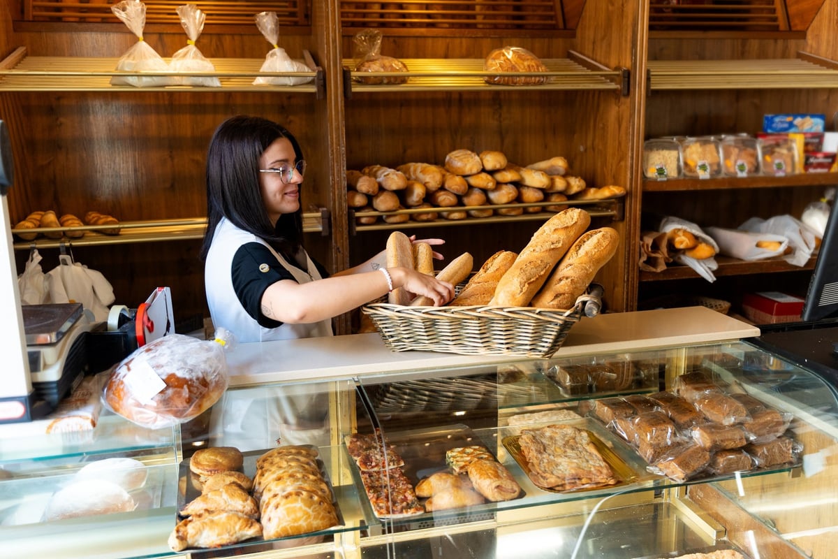 Bakker in de winkel met vers brood en gebak